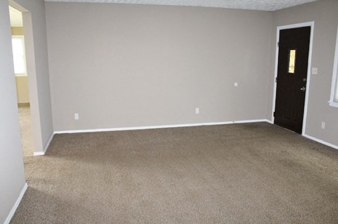 an empty living room with carpet and a door