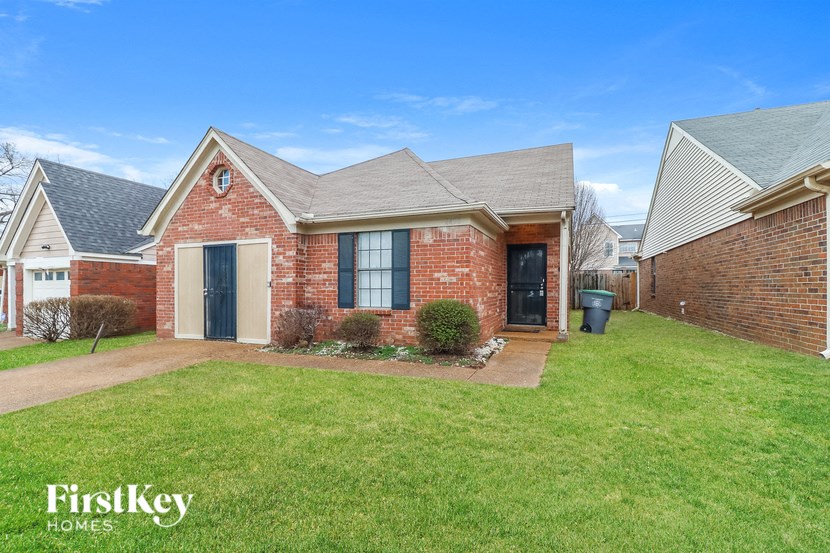A brick house with a black door and a small front yard.