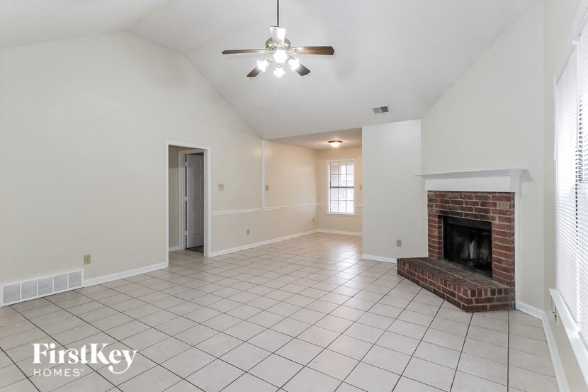 A spacious living room with a fireplace and a ceiling fan.