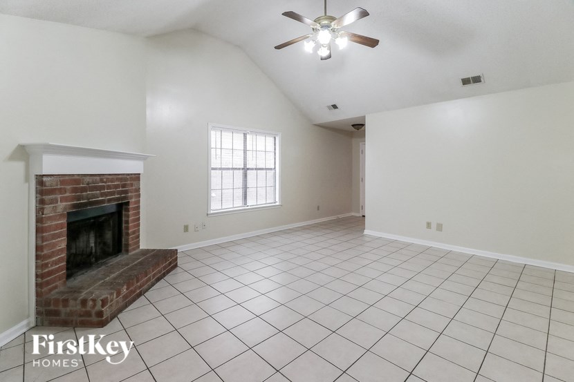 A spacious living room with a fireplace and a ceiling fan.