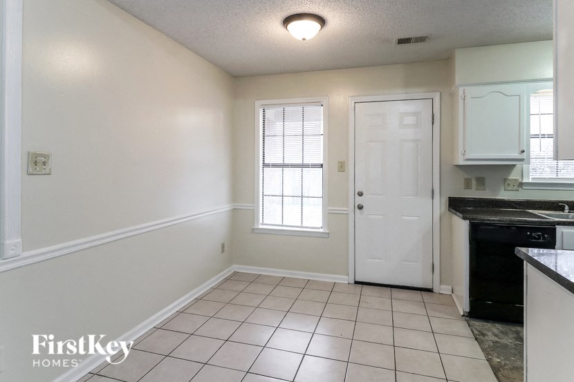 A kitchen area with a white door and a window with blinds.