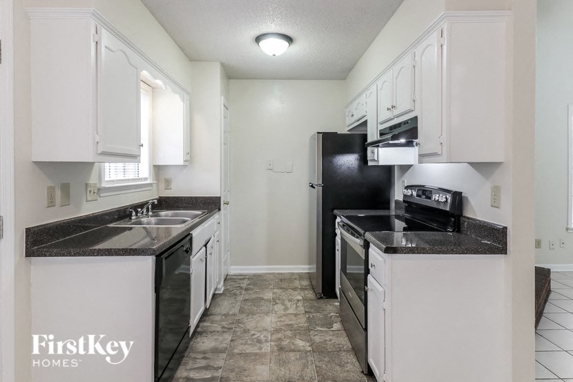 A kitchen with black appliances and white cabinets.