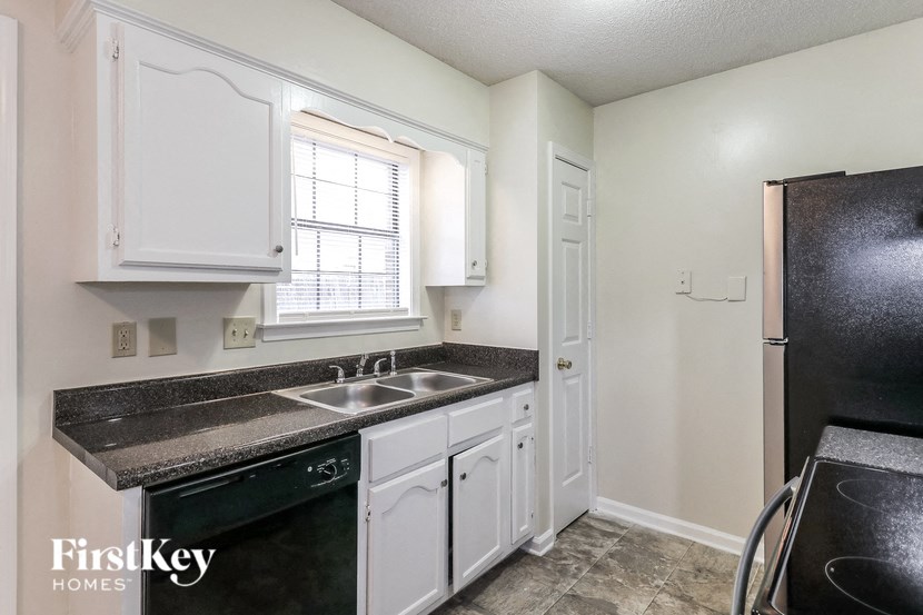 A kitchen with black countertops and white cabinets.