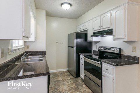 A kitchen with a black fridge and stove top oven.