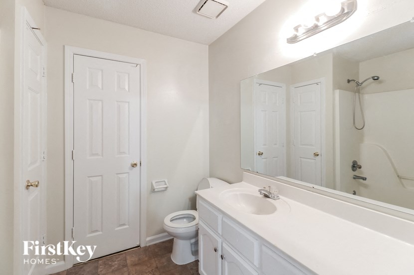 A white bathroom with a toilet, sink, and mirror.