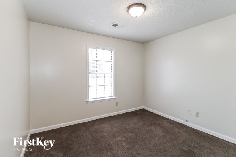 A room with a window and carpeted floor.