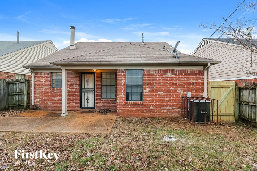 A brick house with a black trash bin in front of it.