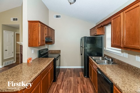 A kitchen with wooden cabinets and a black fridge.