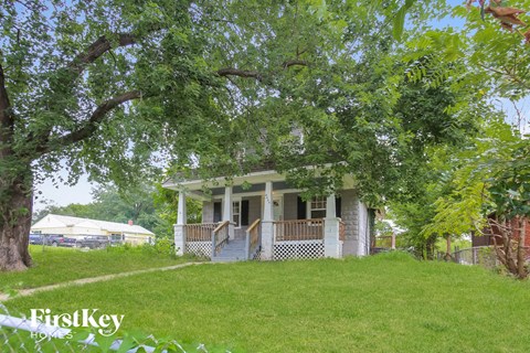 A house with a porch is surrounded by trees.