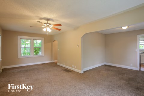 A spacious room with a carpeted floor and a ceiling fan.