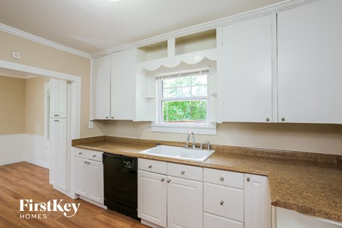 A kitchen with white cabinets and a black dishwasher.