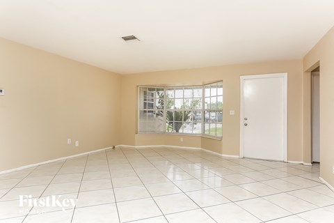 A spacious room with a white door and a window.