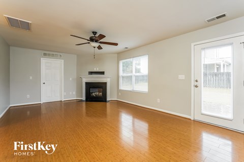 A spacious living room with a fireplace and a ceiling fan.