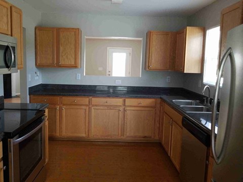 A kitchen with wooden cabinets and black countertops.
