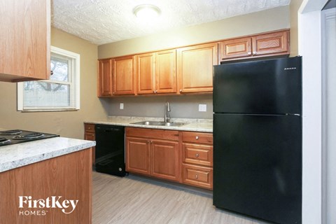 A kitchen with wooden cabinets and a black fridge.