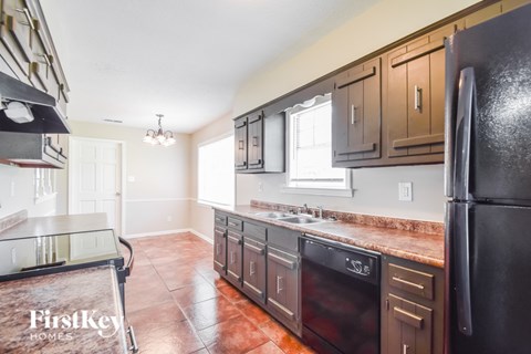 A kitchen with brown cabinets and a black refrigerator.