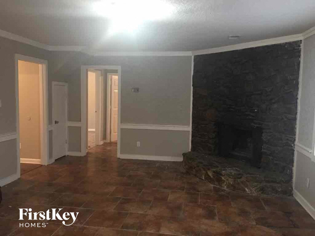A room with a stone fireplace and tile flooring.
