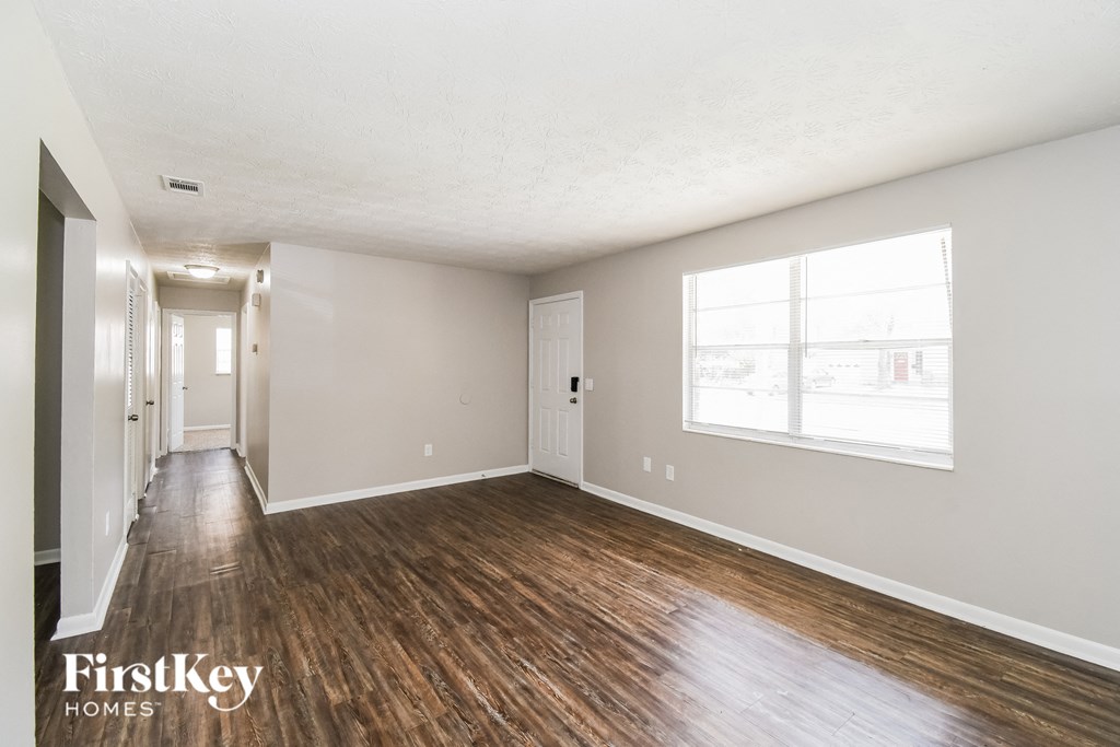 an empty living room with wood floors and a large window