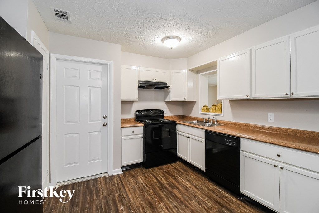 a kitchen with white cabinets and black appliances
