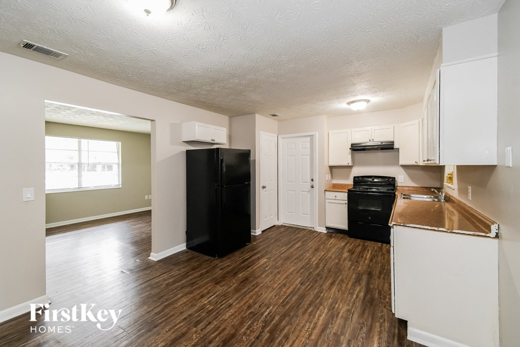 an empty kitchen with white cabinets and a black stove and refrigerator