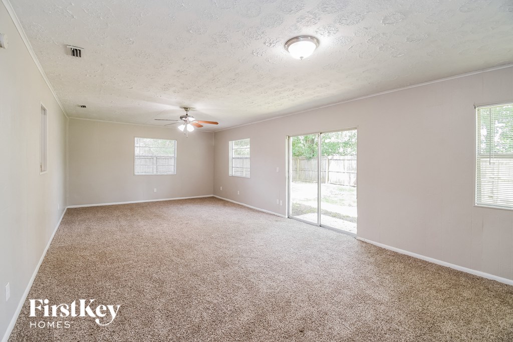 a spacious living room with carpet and a ceiling fan