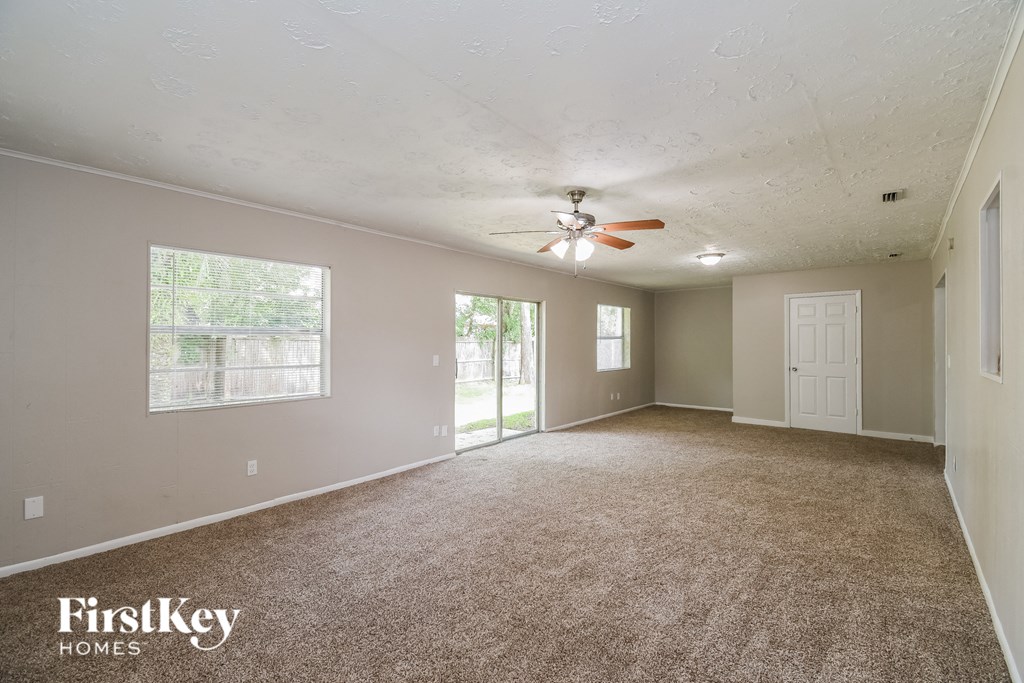 an empty living room with carpet and a ceiling fan