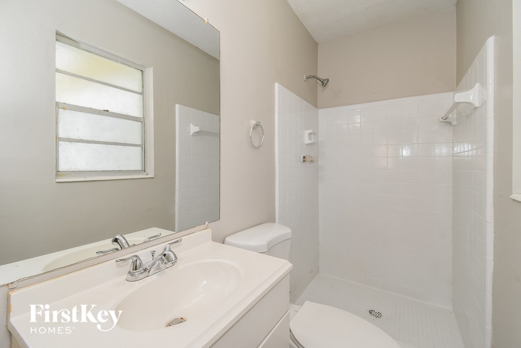 a white bathroom with a sink toilet and shower