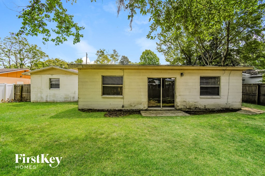 a small yellow and in a backyard with grass and trees