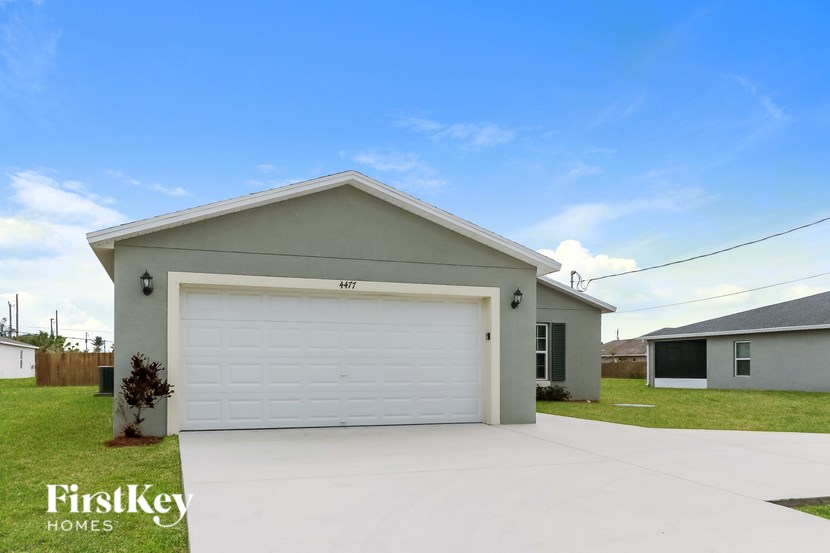 A two-car garage with a white door is situated in a grassy area.
