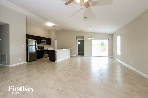 A spacious kitchen and living room with a ceiling fan and lighting fixtures.