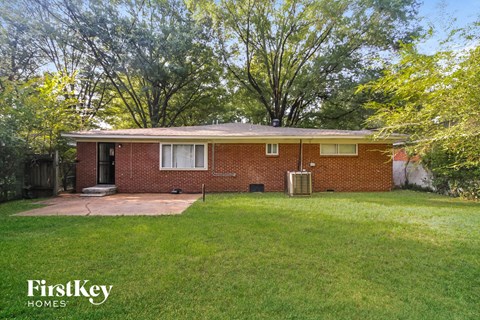 the front of a brick house with a yard and grass