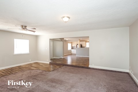 a living room with a carpet and a ceiling fan