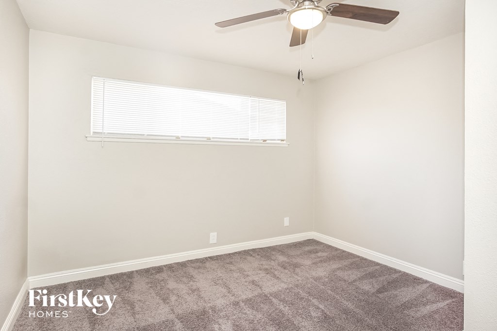 a bedroom with carpet and a ceiling fan and a window