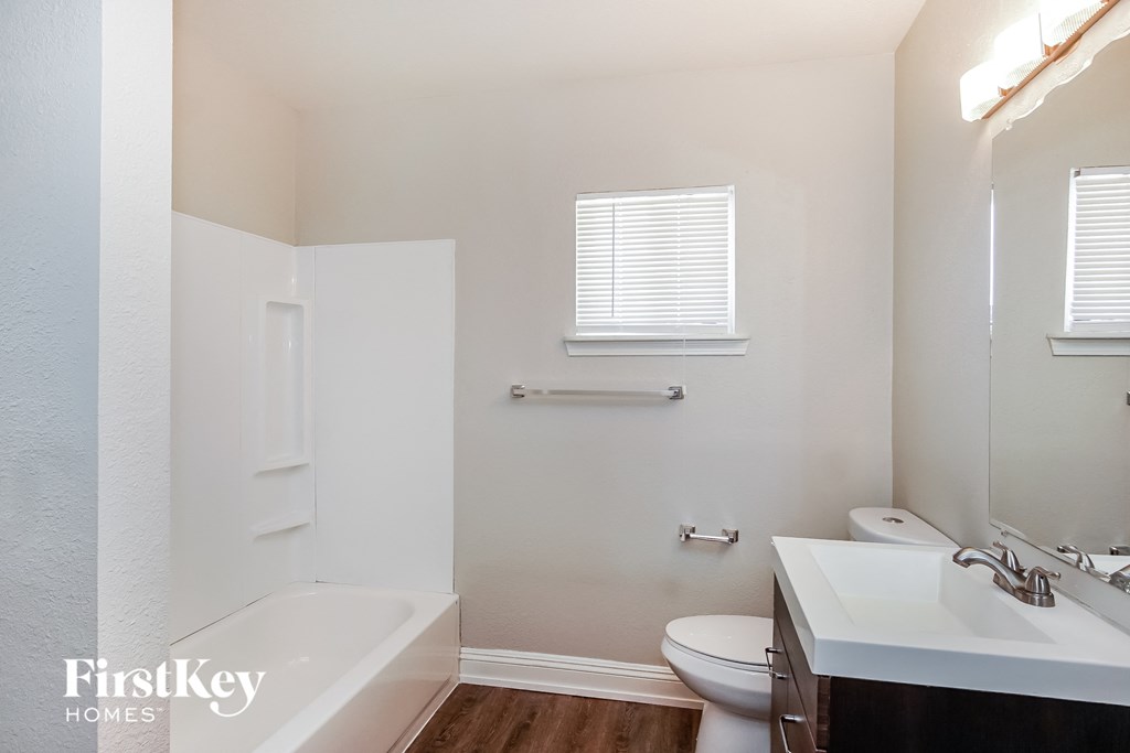 a bathroom with a sink toilet and bath tub and a sink and toilet paper roll