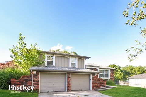a house with two garage doors and a sidewalk in front of it