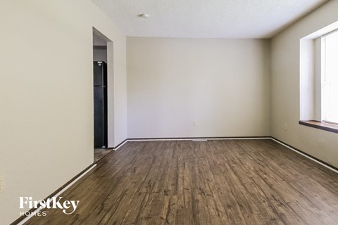 the living room of an apartment with wood flooring and white walls