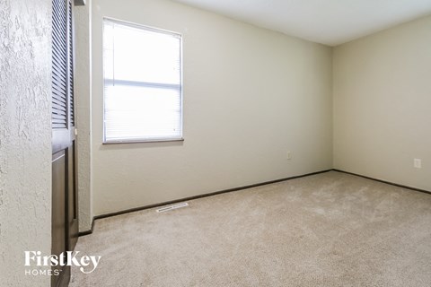 a bedroom with a window and a carpeted floor
