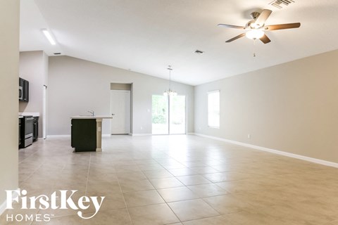 A spacious room with a ceiling fan and a kitchen area with a fridge and stove.