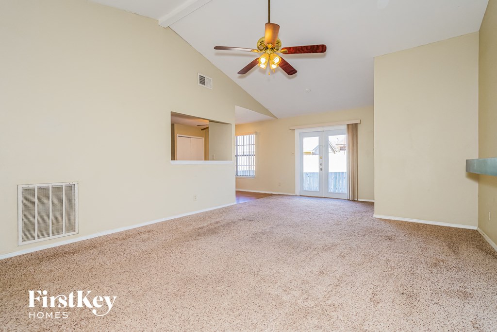 an empty living room with a ceiling fan and a window