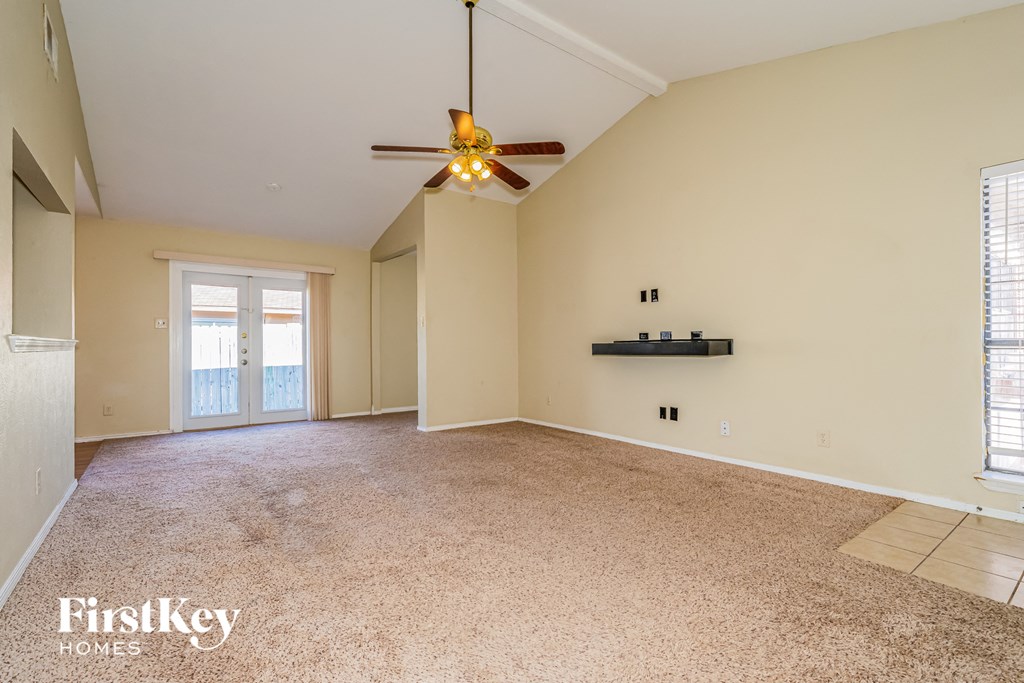 an empty living room with a ceiling fan