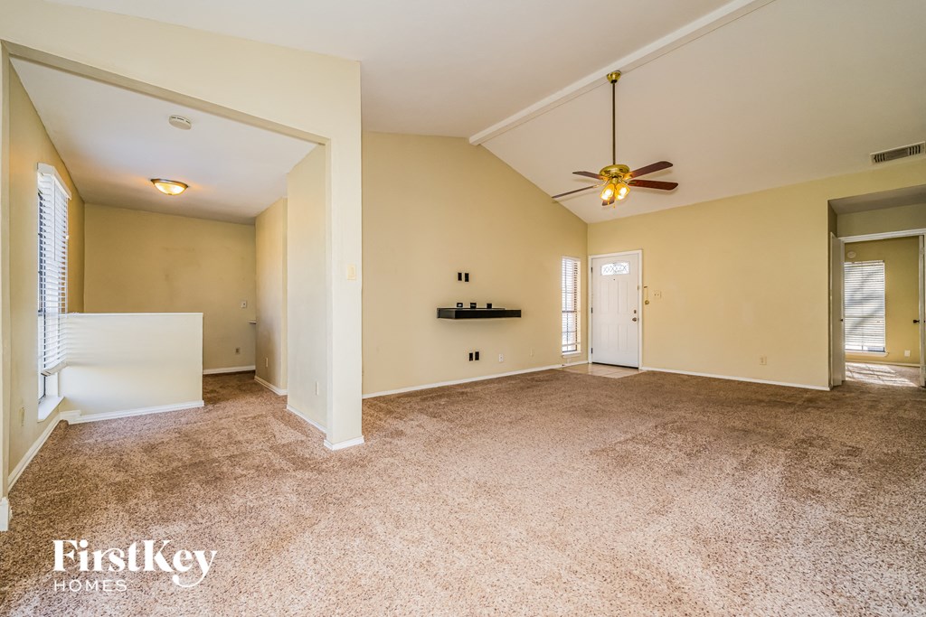 an empty living room with a ceiling fan