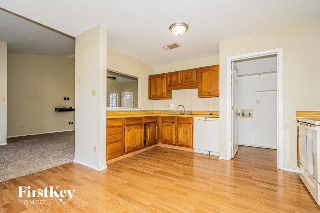 an empty kitchen and living room with wood floors and white walls