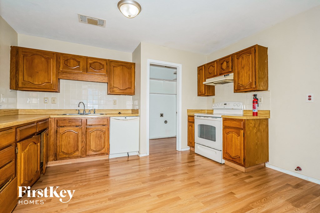 a kitchen with wooden cabinets and white appliances and a wooden floor