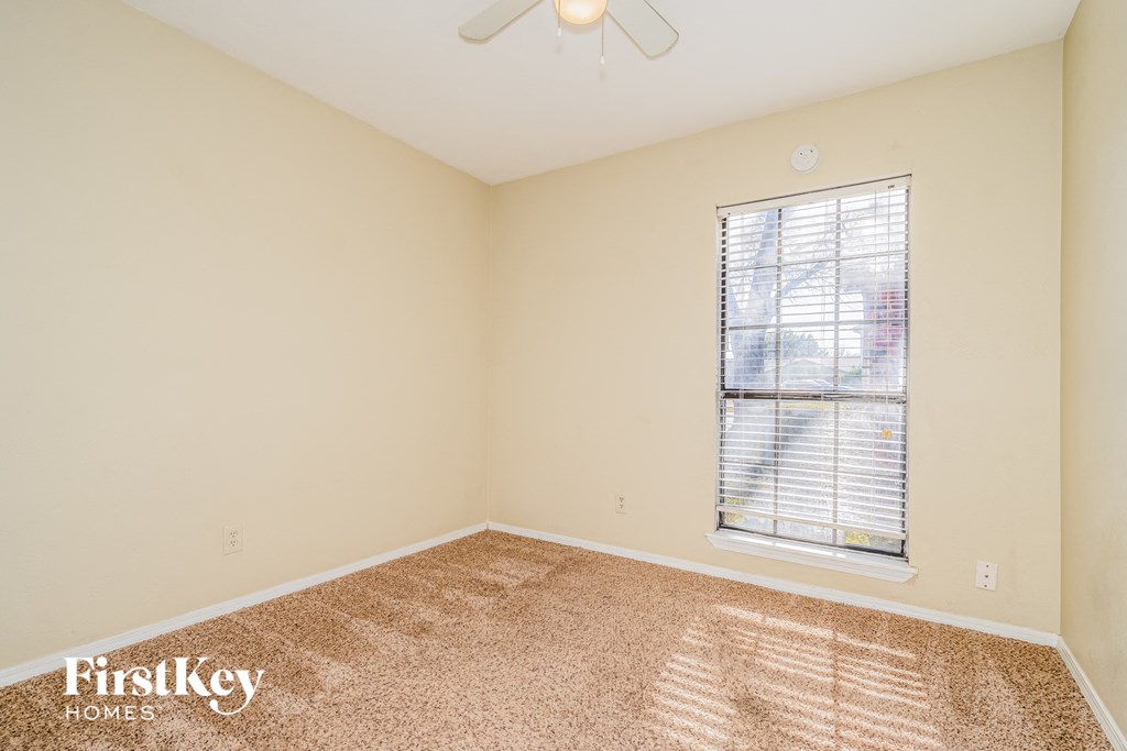 the living room of a studio apartment with carpet and a window