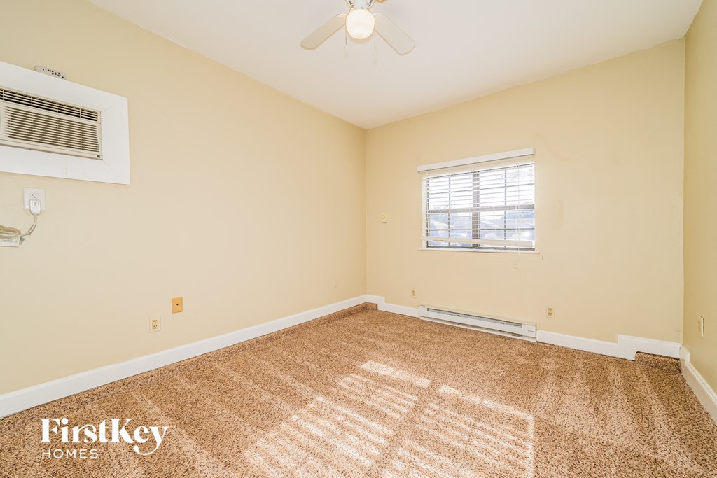the living room is spacious and clean with carpet and a ceiling fan