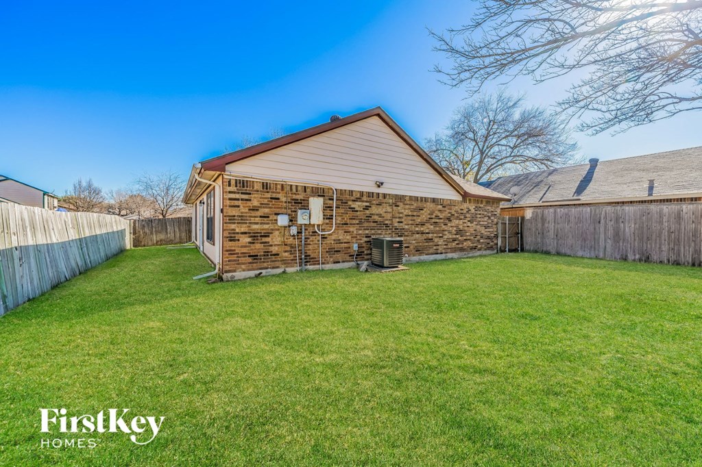 a backyard with a brick house and a green lawn