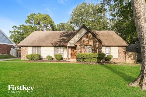 A house with a brown roof and a tree in front.