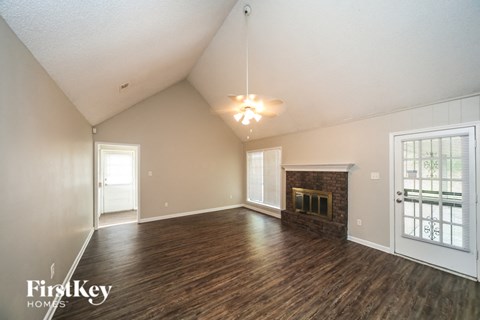 A large empty room with a fireplace and wooden floors.