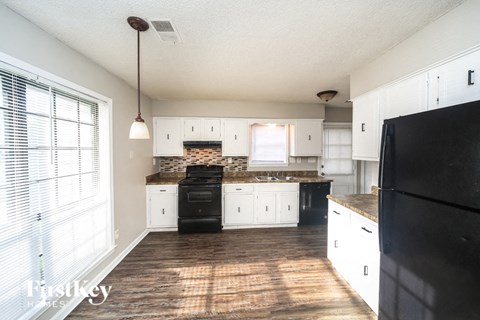 A kitchen with black appliances and white cabinets.