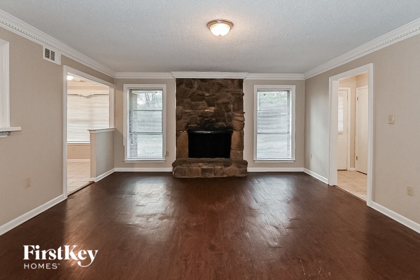 a living room with a stone fireplace and wood floors